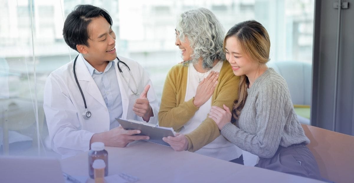 A doctor giving a thumbs-up while explaining senior care and helping an older adult and caregiver understand incontinence.