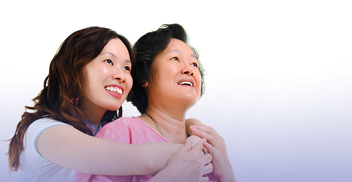 A young caregiver embracing an older loved one to support her through senior incontinence management.
