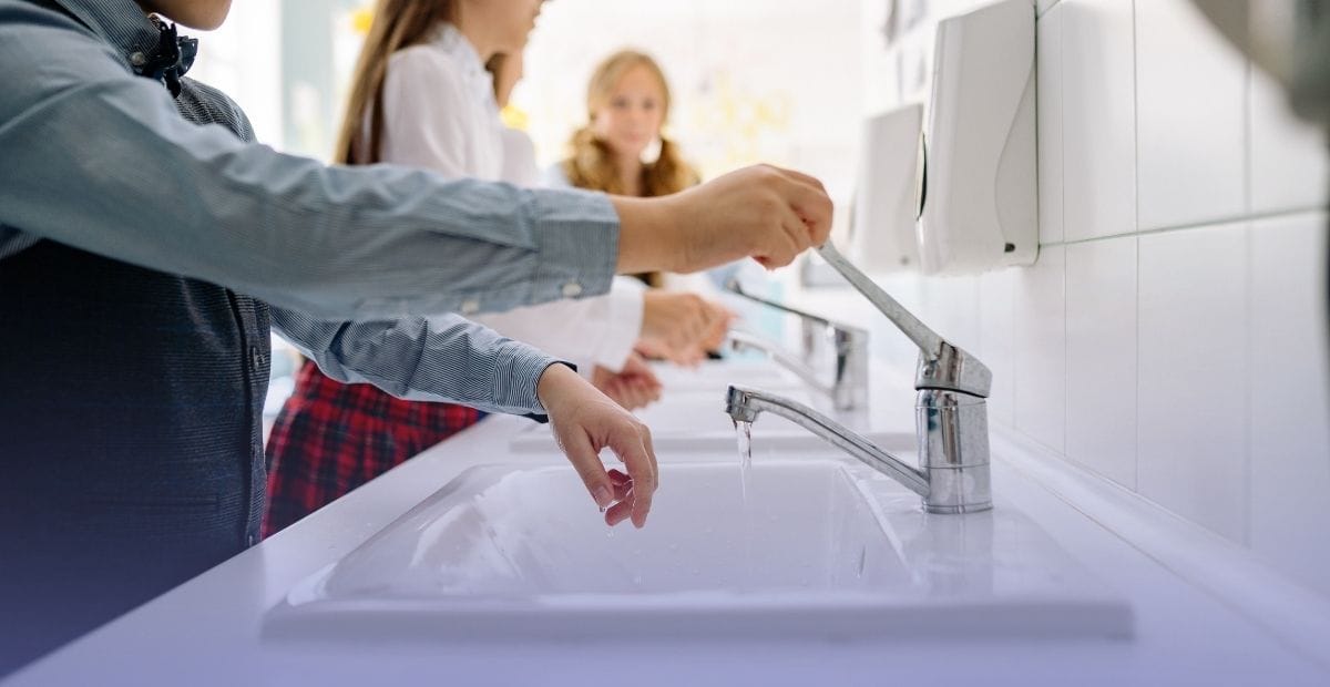 Children washing hands in a school restroom, illustrating daily hygiene routines